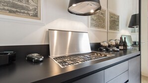 A modern kitchen with a stainless steel range hood, a black countertop, and decorative items including a car model and wine bottles. - Smart and design flat in Brera close to Alla Scala theatre (Milano)
