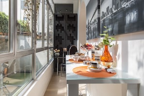 Un coin repas moderne avec une table en verre, des sets de table orange et un vase décoratif.