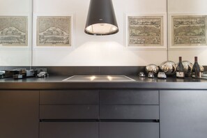 A modern kitchen with a central island, overhead lighting, and framed artwork on the walls. - Smart and design flat in Brera close to Alla Scala theatre (Milano)