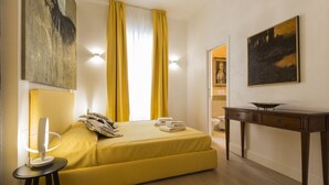 A room with a bed, a bedside table, a lamp, a painting, and a window with curtains. - Smart and design flat in Brera close to Alla Scala theatre (Milano)
