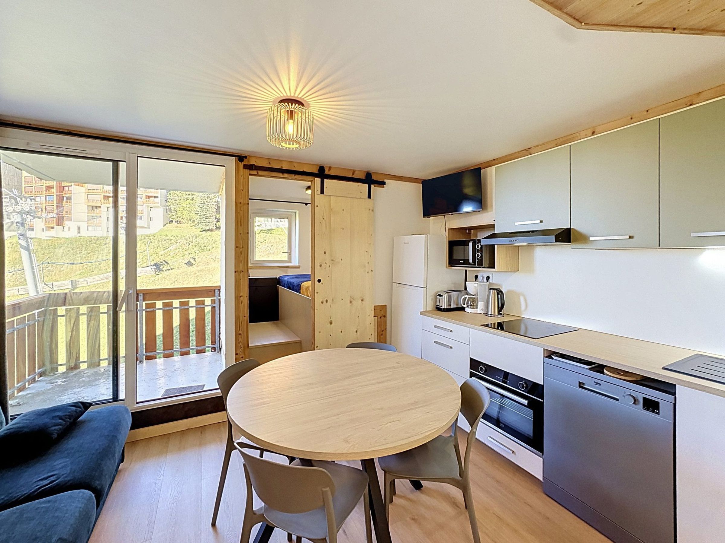A compact kitchen with a dining area, a built-in oven, and a TV mounted above the counter.