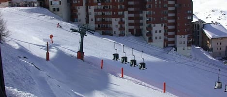 Een skigebied met een stoeltjeslift, gebouwen en een besneeuwde berg op de achtergrond.