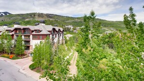 A mountain lodge with multiple buildings, a dirt path, and surrounding greenery. - Centennial 3 (Avon)