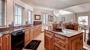 A spacious kitchen with wooden cabinets, a dishwasher, and a large island. - Centennial 2 Bedroom Condo Unit no. 16 (Avon)