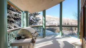Un balcón cubierto con una parrilla, árboles nevados y una vista despejada de un paisaje invernal.
