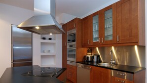 Eine moderne Küche mit Edelstahlgeräten, Holzschränken und einer schwarzen Arbeitsplatte.