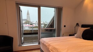 Ein Schlafzimmer mit großem Fenster, einem Bett, einem Sessel und einer Heizung.