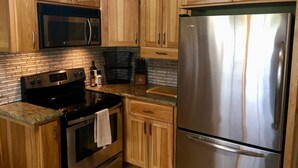 A kitchen with wooden cabinets, stainless steel appliances, and a tiled backsplash. - Racing Horse Ranch and Guest House with Golf (Grants Pass)