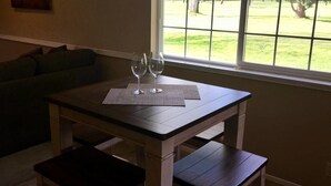 A dining table with two wine glasses and a placemat, set against a window with a view of a grassy yard. - Racing Horse Ranch and Guest House with Golf (Grants Pass)