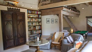 Un vaste espace de vie doté d’un haut plafond, d’une grande bibliothèque, d’une table de billard et d’un coin salon confortable.