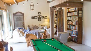Une pièce chaleureuse avec une table de billard, un canapé confortable, une bibliothèque et une grande porte en bois.