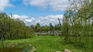 A natural landscape with a pond, rocks, and a wooden fence. - Hopyard View Farm - A Farm Experience in Ashland (Ashland)