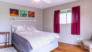 A bedroom with a bed, a wooden floor, a window with red curtains, and wall art. - Hopyard View Farm - A Farm Experience in Ashland (Ashland)