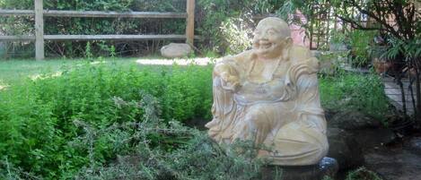 A garden statue surrounded by dense greenery and a wooden fence.