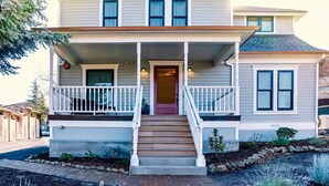 A two-story house with a front porch, a red door, and a small garden with a pond. - Redtail Suites ~ Entire Home ~ Sleeps 12 ~ Tesla Station (Ashland)