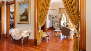 A room with wooden flooring, a large painting on the wall, and a seating area with a sofa and chairs. - Jacksonville's Historic Nunan House (Jacksonville)