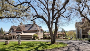 A residential area with two houses, a large tree, and a statue in the foreground. - Jacksonville's Historic Nunan House (Jacksonville)