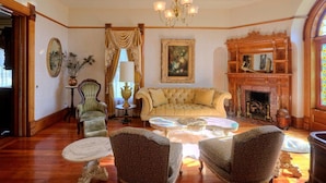 A traditional living room with a sofa, two armchairs, a fireplace, and a chandelier. - Jacksonville's Historic Nunan House (Jacksonville)