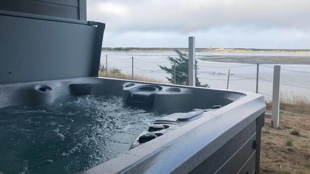 Ein Whirlpool mit Blick auf einen Strand und einen bewölkten Himmel.
