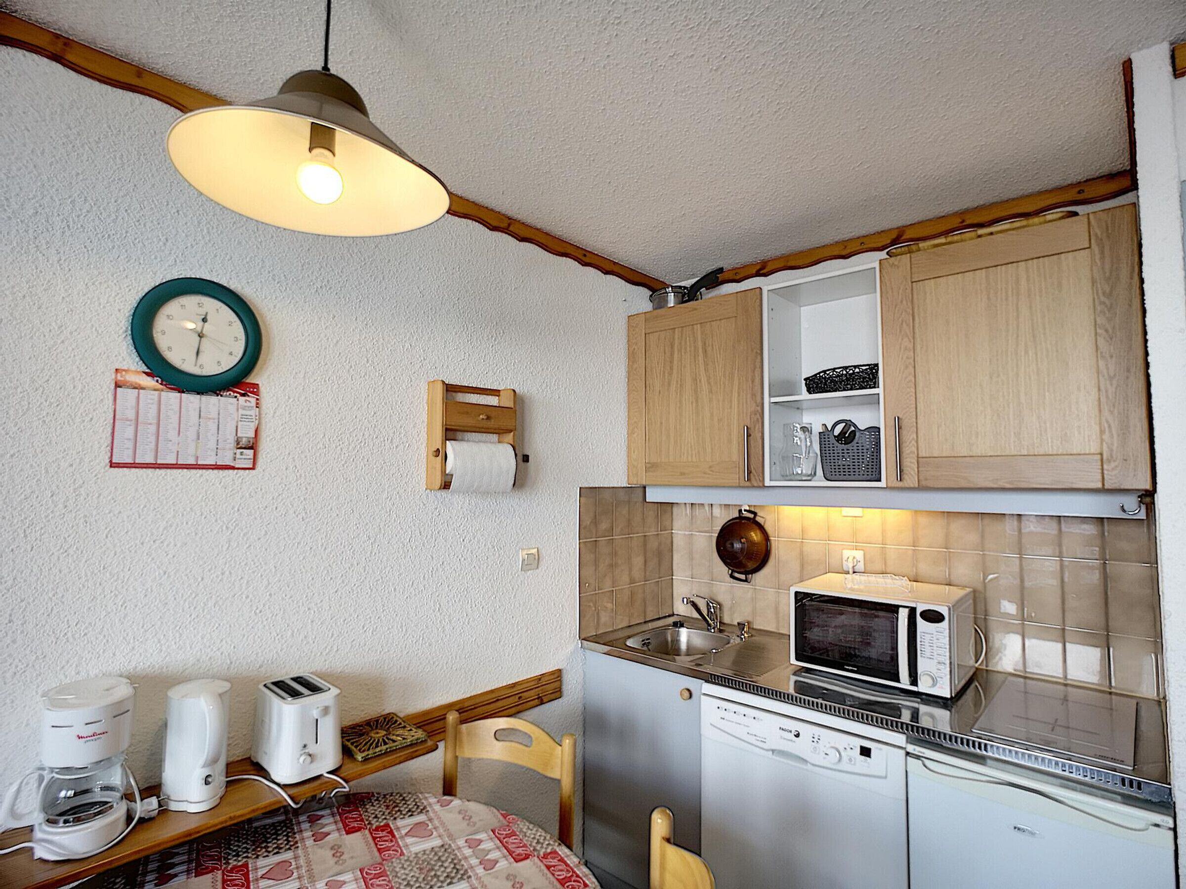 A compact kitchen with wooden cabinets, a microwave, a toaster, and a coffee maker.