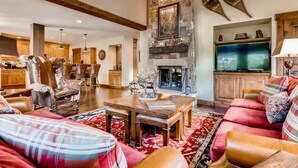 A spacious living room with a fireplace, wooden furniture, and a television. - Centennial 4 Bedroom Condo Unit no. 29 (Avon)