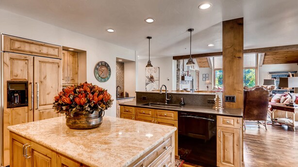 A spacious kitchen with wooden cabinets, a granite countertop, and a central island with a flower arrangement. - Centennial 4 Bedroom Condo Unit no. 29 (Avon)