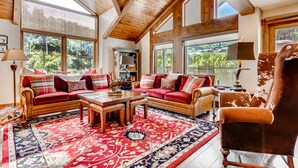 A spacious living room with a large red and blue patterned rug, a wooden coffee table, and a leather sofa with red cushions. - Centennial 4 Bedroom Condo Unit no. 29 (Avon)
