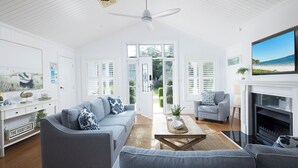 A bright living room with a sofa, armchairs, a coffee table, and a fireplace.