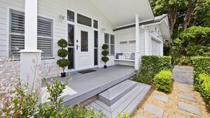 A white house with a porch, a bench, and a small garden.