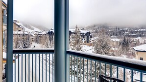 A balcony with a view of a snow-covered town and mountains. - Centennial 1 Bedroom Condo Unit No. 13b (Avon)
