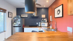 A modern kitchen with a wooden countertop, a built-in oven, a microwave, and a sink.