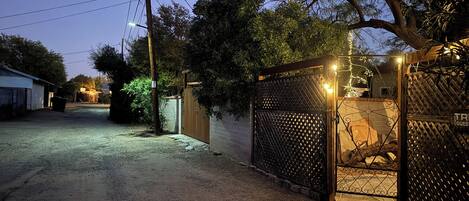 A gated driveway leading to a house with a wooden gate and a metal fence.
