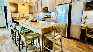 Un'ampia cucina con una grande isola, pavimento in legno e elettrodomestici moderni.