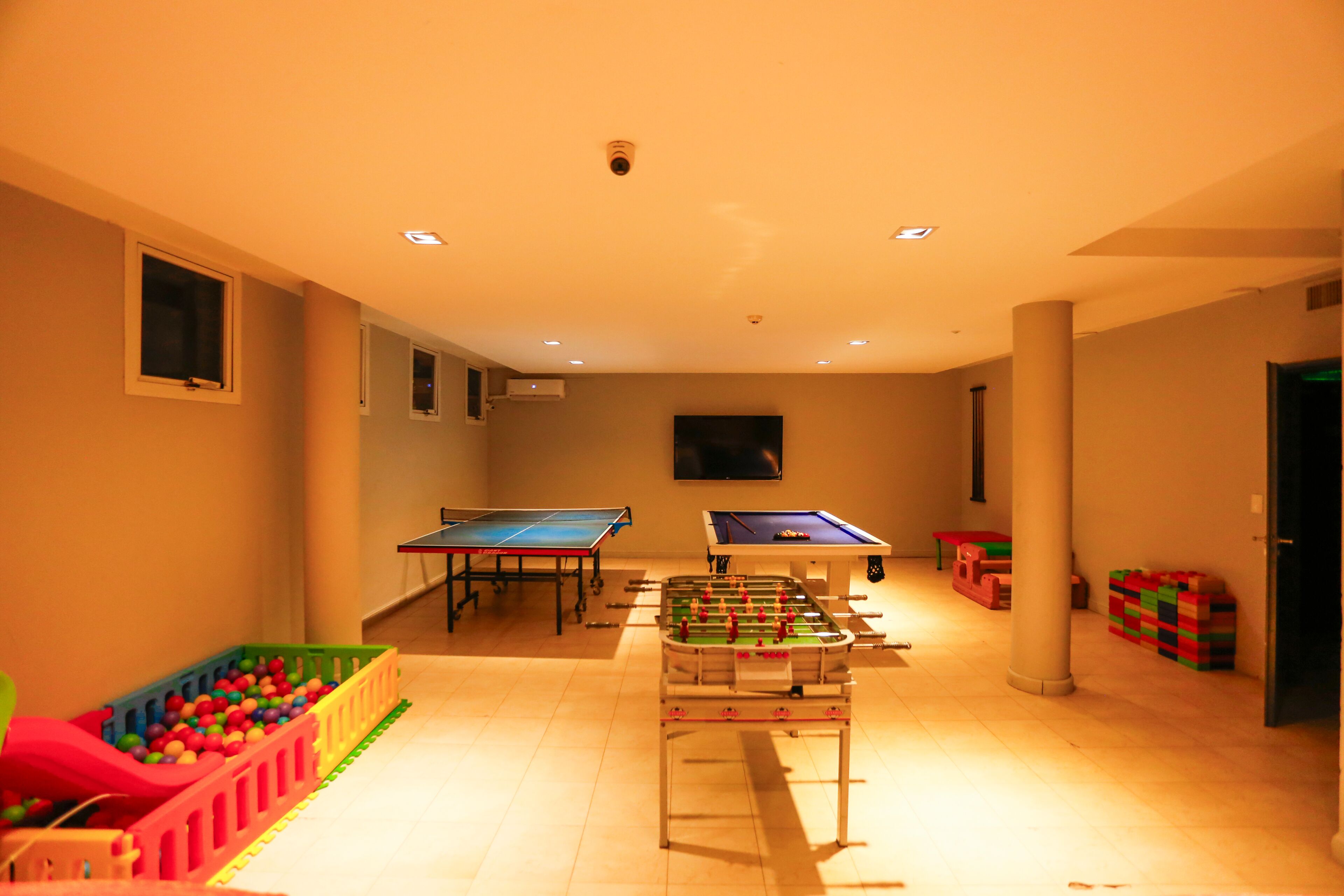 Una habitación con mesa de fútbol, mesa de ping pong y mesa de billar.