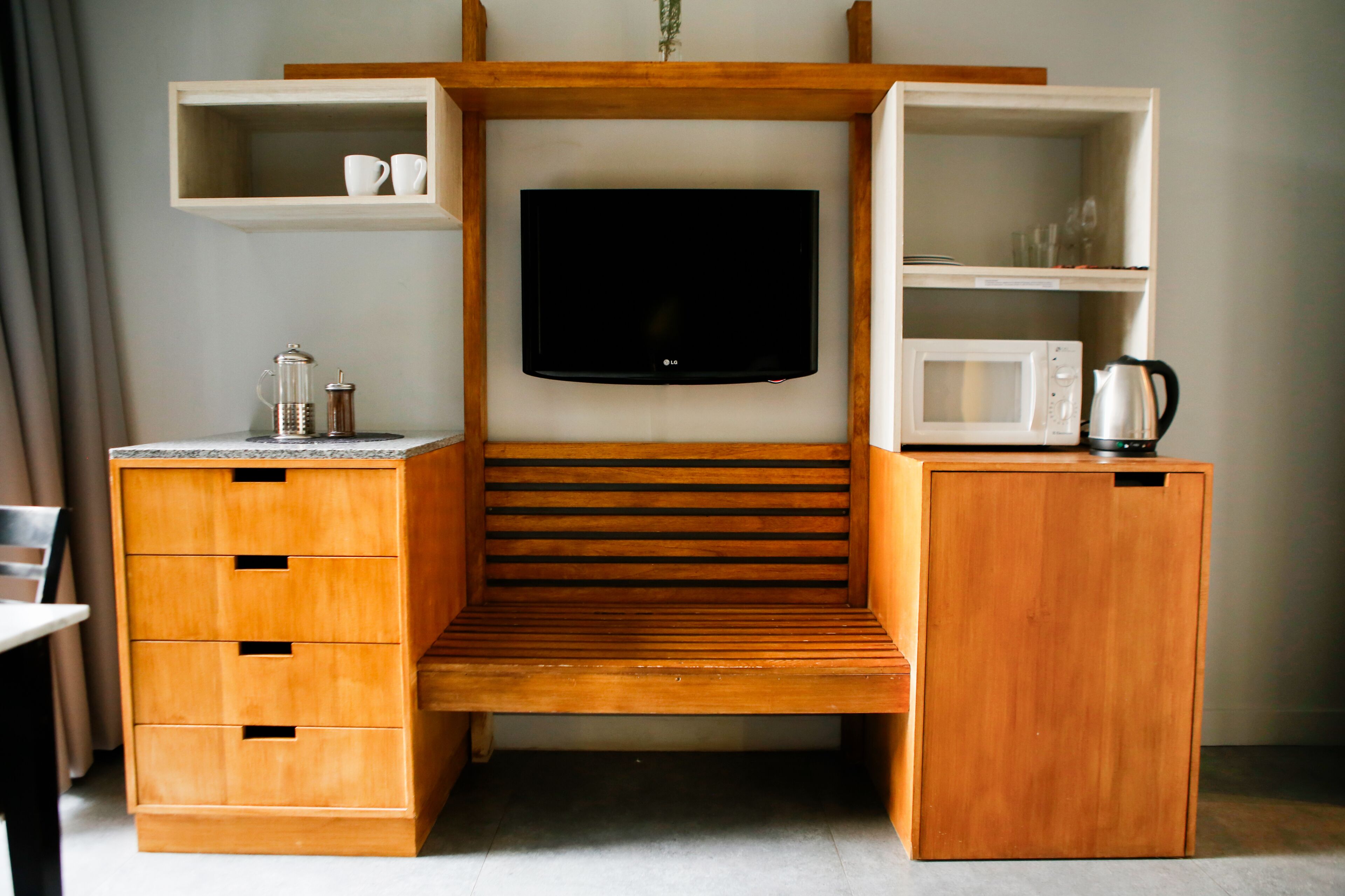 Un espacio habitable compacto con televisión integrada, armarios de madera, microondas y cafetera.