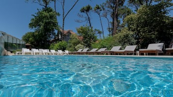 Una piscina techada, una piscina al aire libre de temporada, sombrillas