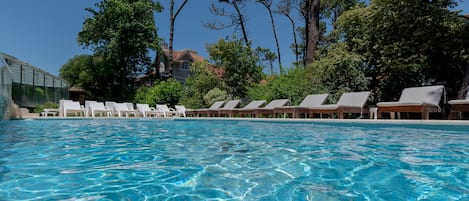 Una piscina techada, una piscina al aire libre de temporada, sombrillas