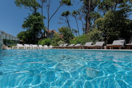 Una piscina techada, una piscina al aire libre de temporada, sombrillas