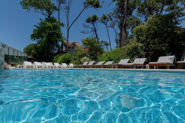 Una piscina cubierta, una piscina al aire libre de temporada, sombrillas