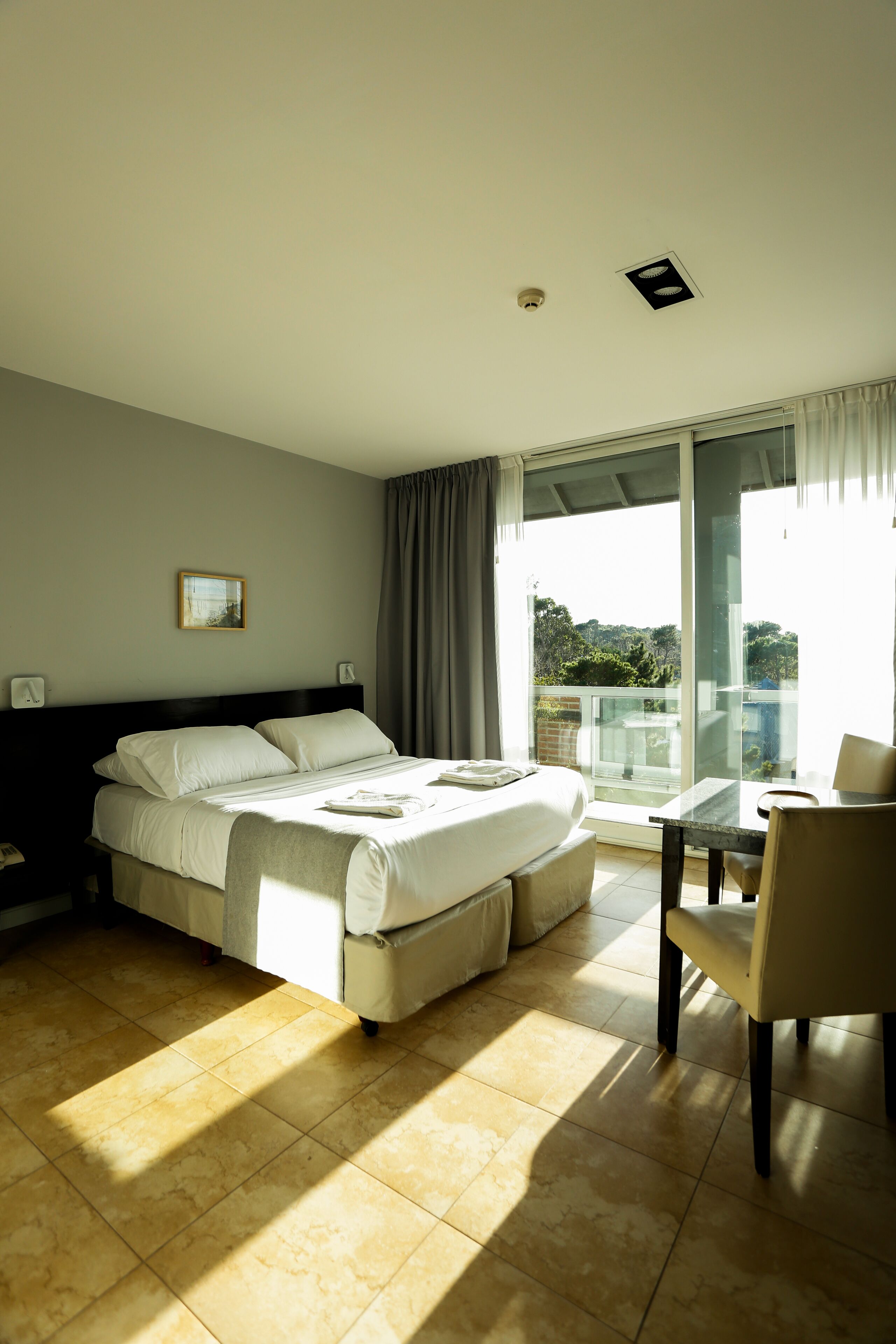 A hotel room with a bed, a table, and a chair.