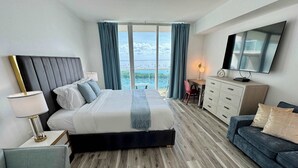 Una habitación de hotel moderna con una cama grande, un escritorio, un sofá y un televisor.