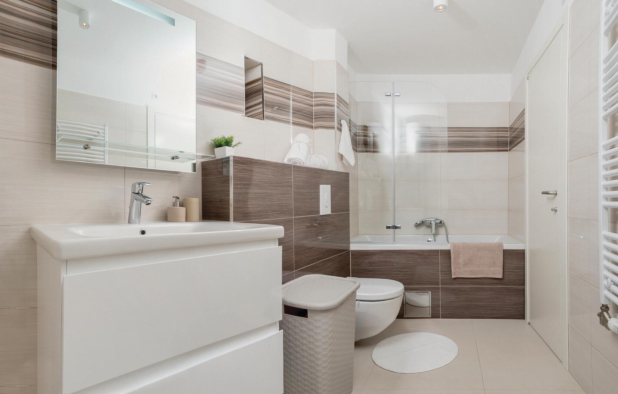Une salle de bain moderne équipée d’un lavabo, de toilettes et d’une zone douche.