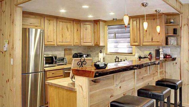Una cocina amplia con armarios de madera, electrodomésticos de acero inoxidable y una isla central con taburetes.