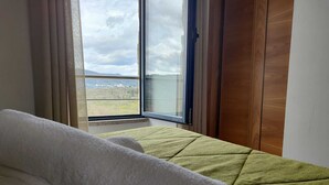 Ein Zimmer mit einem Bett, einem Fenster mit Landschaftsblick und einer Holztür.