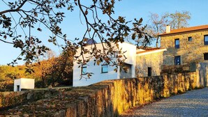 Eine Steinsäule mit einem Kopfsteinpflasterweg, der zu einem weißen Gebäude mit rotem Dach führt.