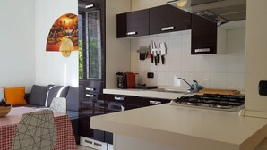 A modern kitchen with black cabinets, a gas stove, and a dining area with a red and white checkered tablecloth.