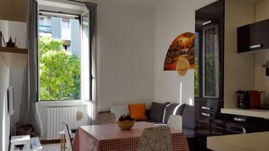 A compact living space with a dining area, kitchenette, and a view of greenery outside.