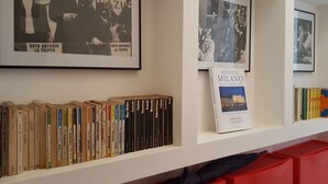 A bookshelf with books and framed pictures on a wall.
