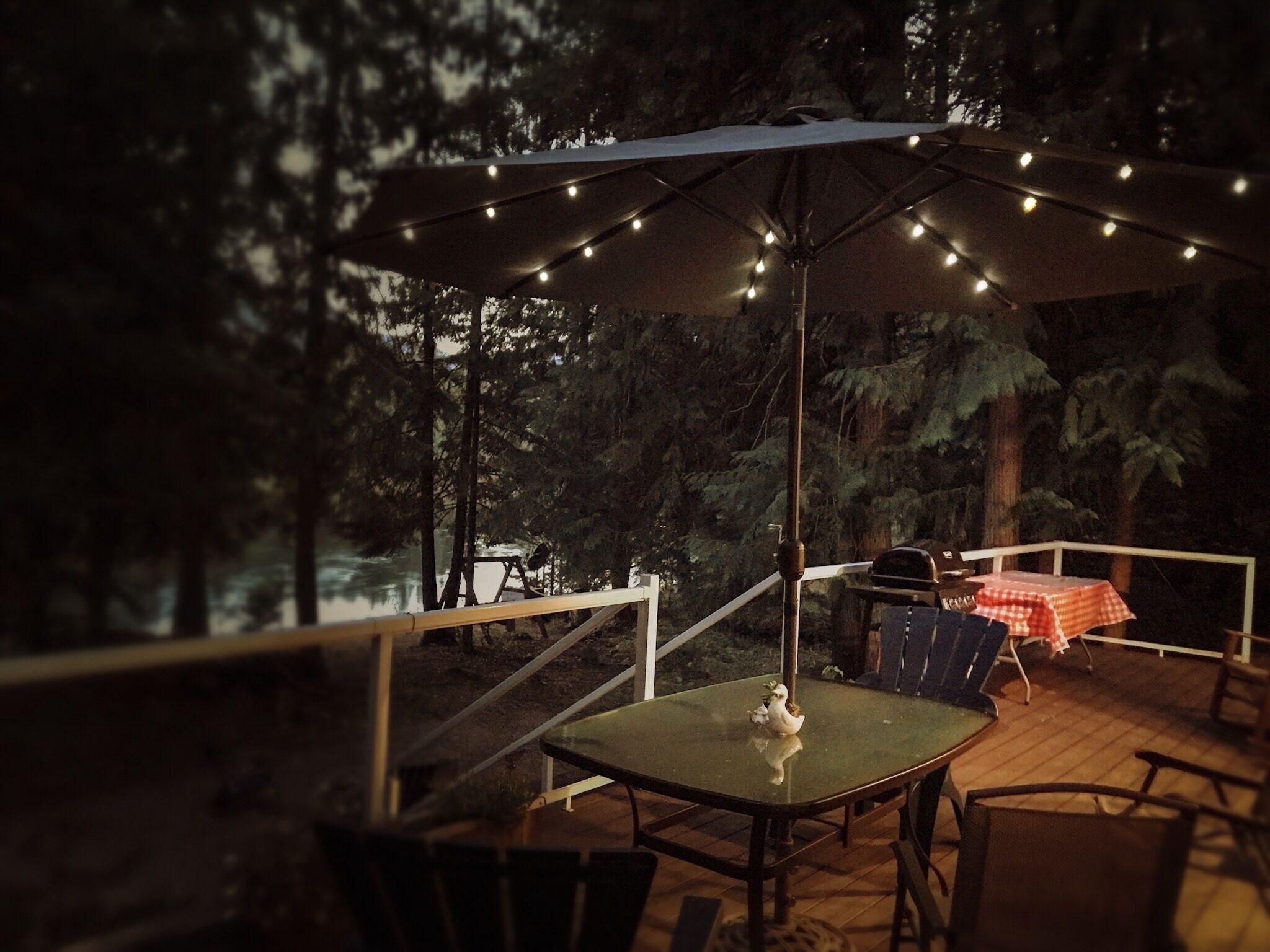 An outdoor patio area with a table and chairs, an umbrella, and string lights.