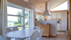 Una cocina moderna con armarios de madera, un comedor con mesa y sillas, y vistas al exterior.